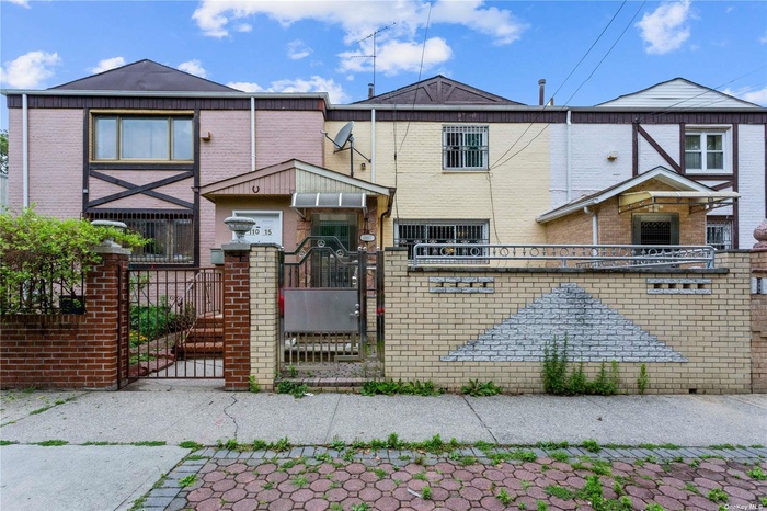 Townhome / multi-family property featuring brick siding, a gate, and a fenced front yard