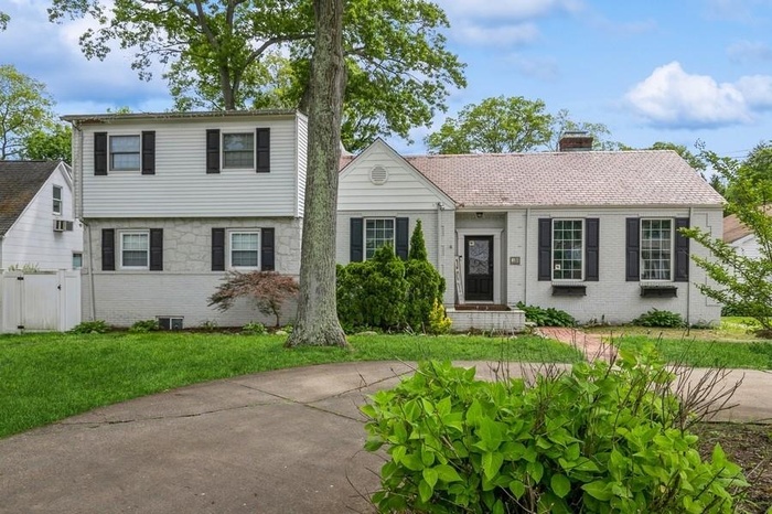 View of front of house featuring brick siding, a chimney, and a gate