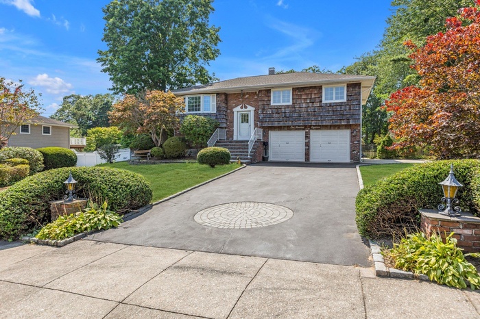 Bi-level home featuring driveway, an attached garage, and a front yard