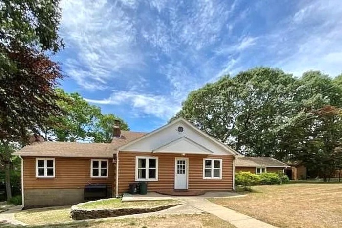 View of front of home featuring a chimney, faux log siding, and a front yard