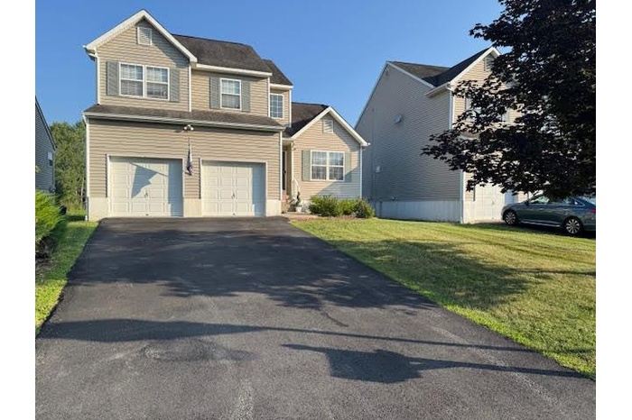 View of driveway, a garage, and a front lawn