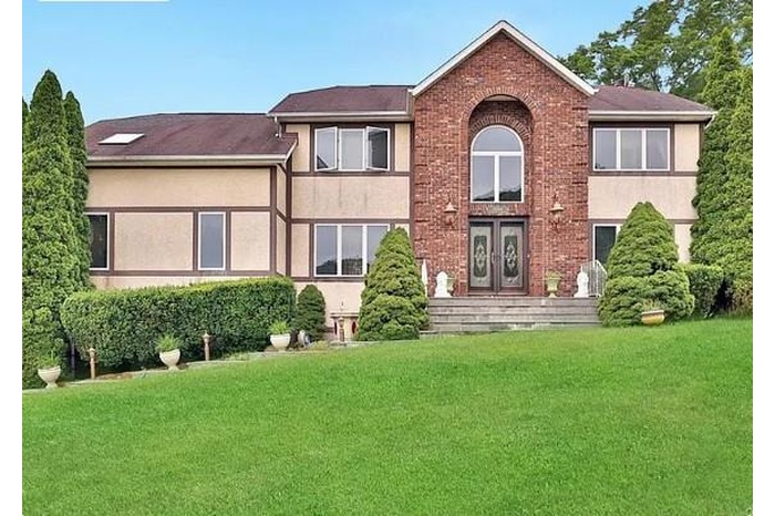 View of front of house with a front lawn, stucco siding, brick siding, and french doors