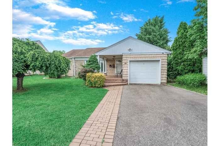 Ranch-style home with a front lawn, a porch, driveway, and an attached garage