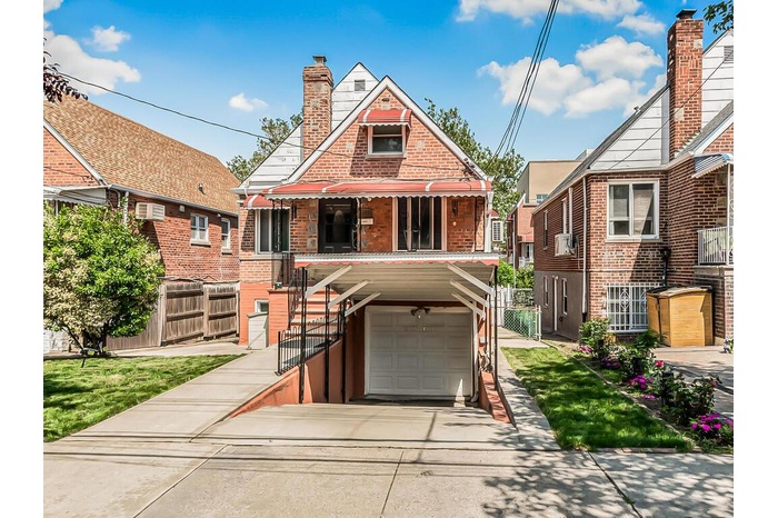 View of front of home featuring a garage, concrete driveway, brick siding, a chimney, and stairway