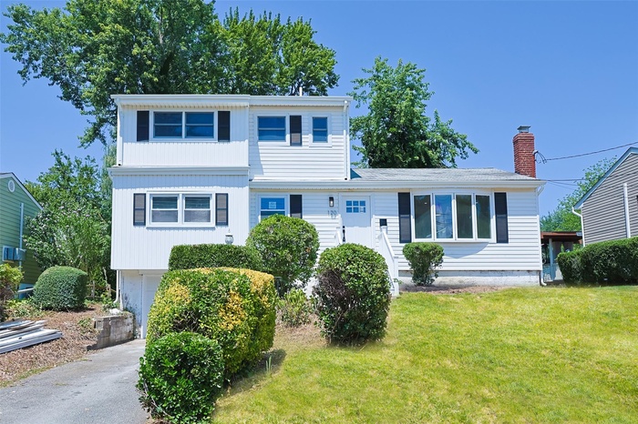 View of front facade with a front yard, driveway, and a chimney