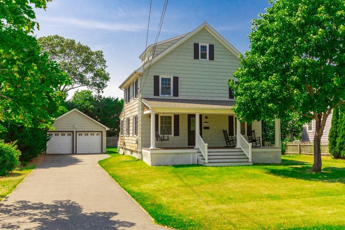 View of front of home with 2 car detached garage, driveway and covered porch