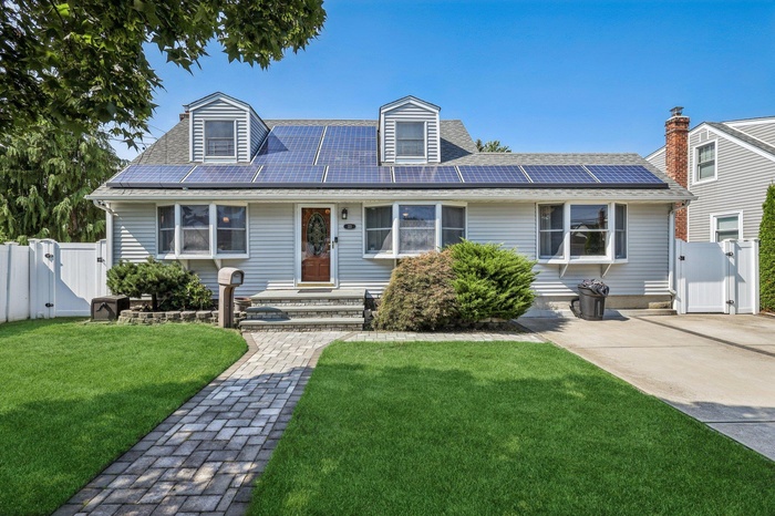 Cape cod-style house featuring a gate and roof mounted solar panels