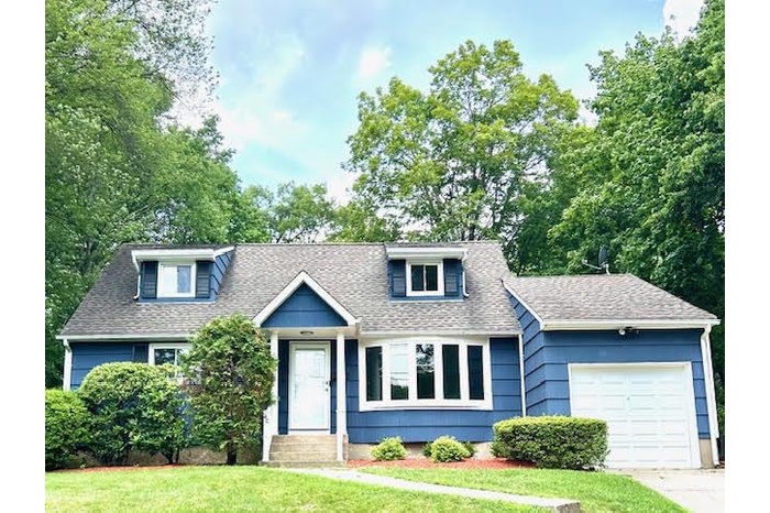 View of front of house featuring a garage, roof with shingles, a front yard, and concrete driveway