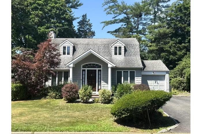 View of front of home featuring an attached garage, a front yard, roof with shingles, and asphalt driveway