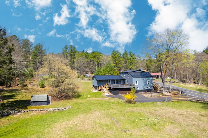 View of yard featuring fence, a view of trees, driveway, and a deck