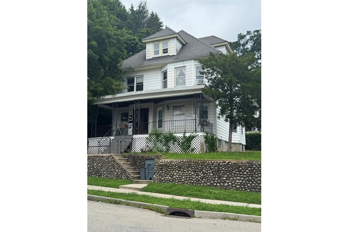 View of front of home featuring stairs, covered porch, and roof with shingles