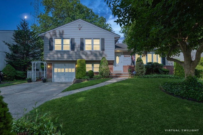 Tri-level home with brick siding, agarage, a front lawn, and driveway