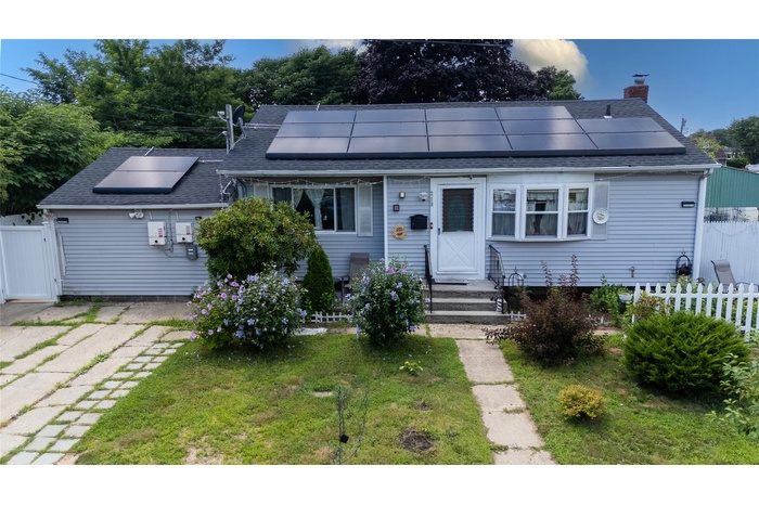 Bungalow featuring solar panels, a chimney, and roof with shingles