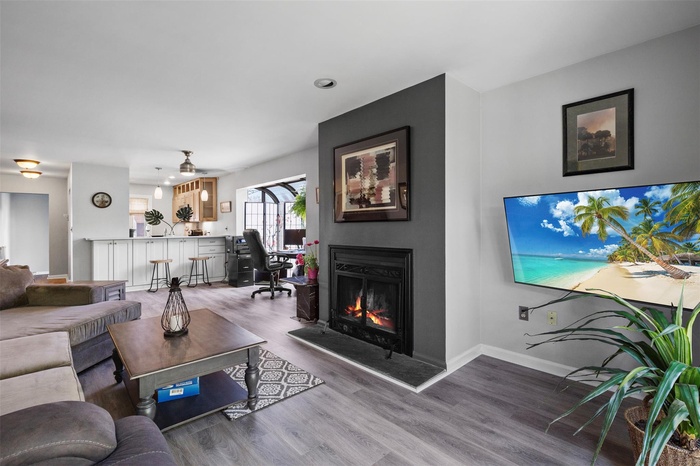 Living area with a fireplace, wood finished floors, recessed lighting, and baseboards