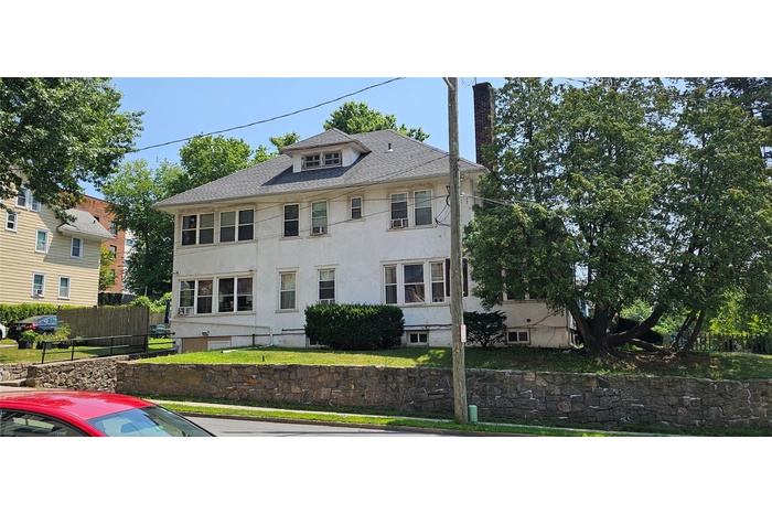 American foursquare style home featuring a chimney, stucco siding, and a shingled roof