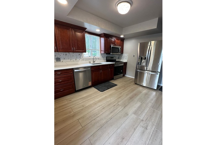 Kitchen featuring a tray ceiling, appliances with stainless steel finishes, light countertops, and recessed lighting