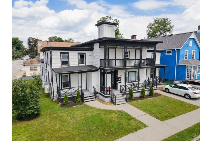 View of front of house with covered porch, a balcony, a chimney, and a front yard