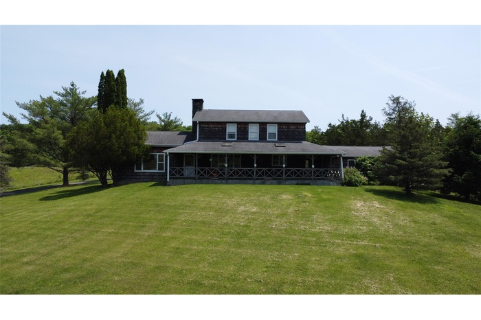 Rear view of house featuring a chimney and a lawn