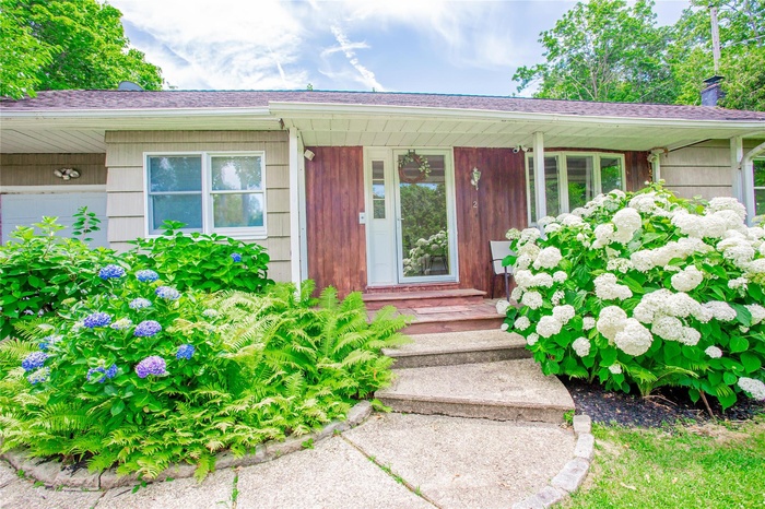 Entrance to property with a chimney, a porch, and a shingled roof