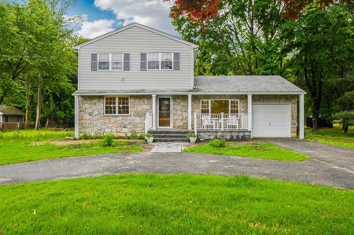 Traditional-style house with stone siding, a porch, and driveway