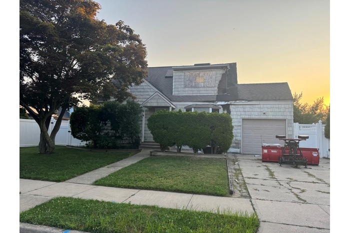 View of front facade featuring an attached garage, driveway, and roof with shingles