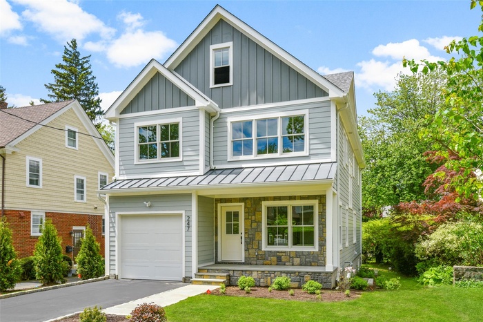 View of front of property with a porch, board and batten siding, a standing seam roof, and a front lawn