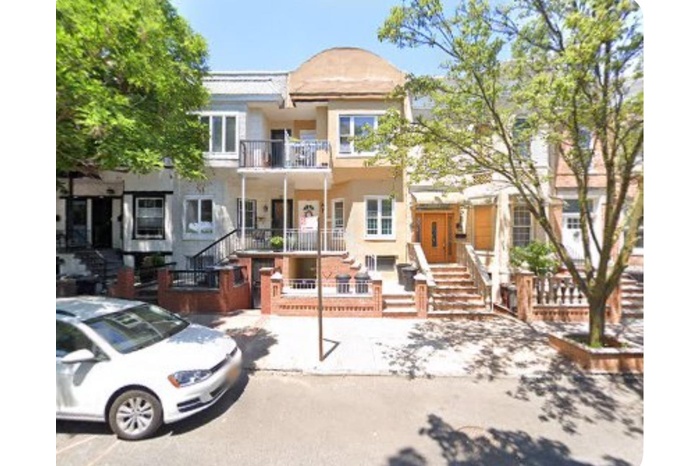 View of front of property featuring stairs, stucco siding, and a balcony
