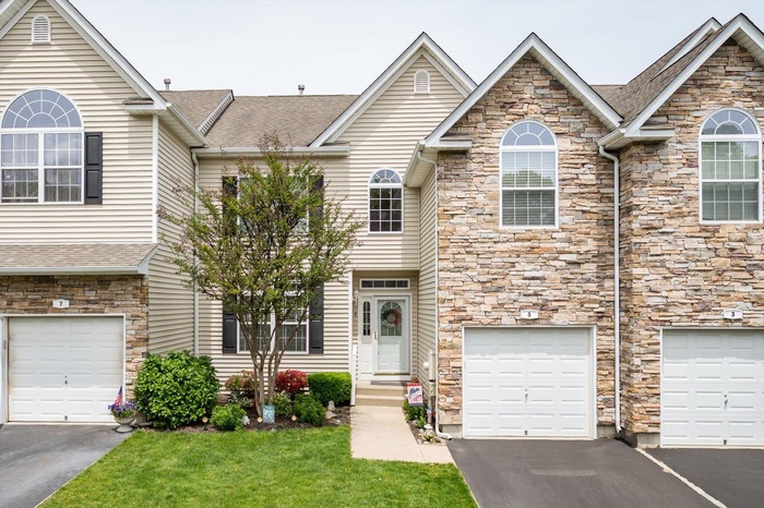Townhome / multi-family property with stone siding, a garage, and driveway