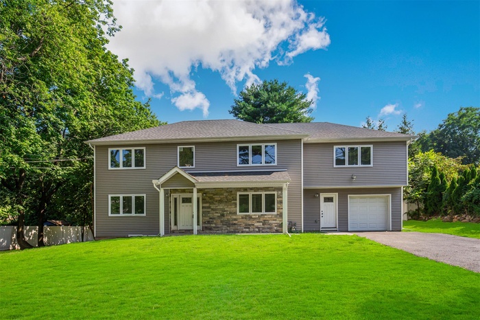 View of front facade featuring asphalt driveway, stone siding, an attached garage, and a porch