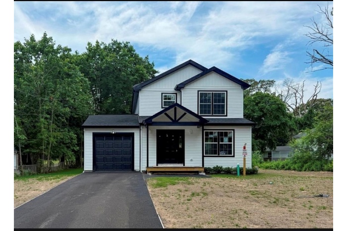 View of front of house with an attached garage and asphalt driveway
