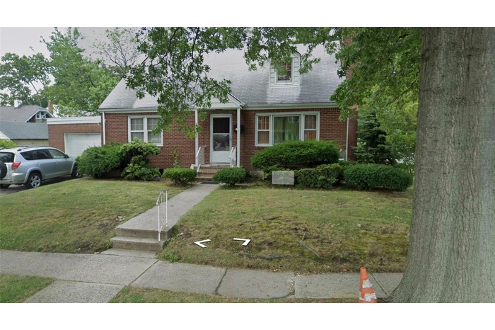 New england style home featuring a front lawn, brick siding, and a garage