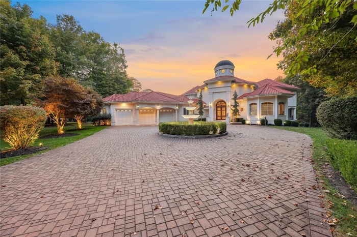 Mediterranean / spanish-style house featuring curved driveway, an attached garage, stucco siding, and a tiled roof