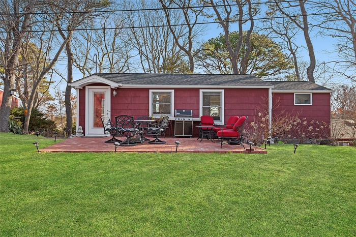 Rear view of house featuring a yard, roof with shingles, and a patio