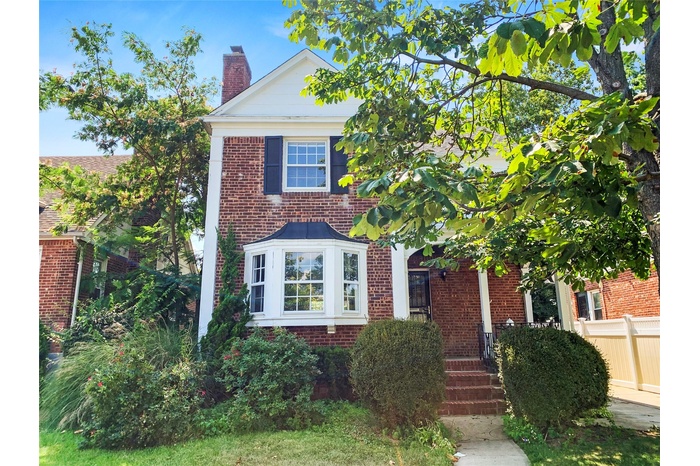 View of front of house featuring a chimney and brick siding
