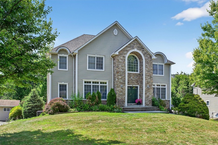 View of front facade with a front lawn and stone siding