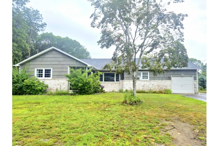 Single story home with brick siding, an attached garage, driveway, and a front lawn