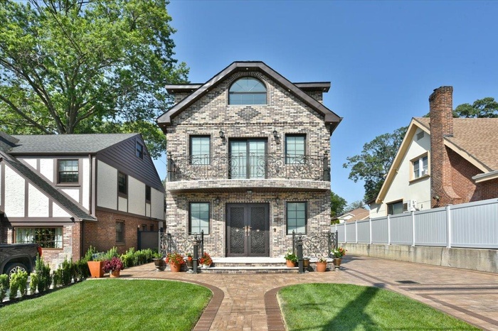 Back of property with french doors, brick siding, and a balcony