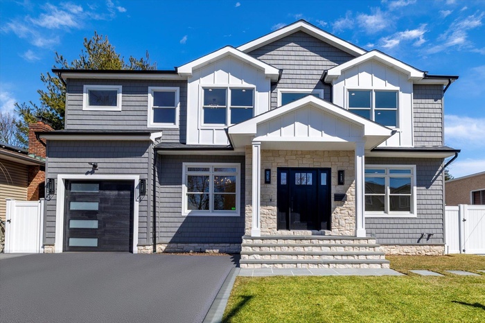 Front exterior featuring board and batten and stone facade with extra wide driveway