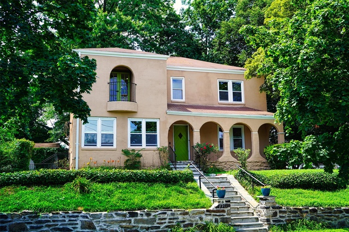 Mediterranean / spanish-style home featuring stucco siding, stairs, and a porch