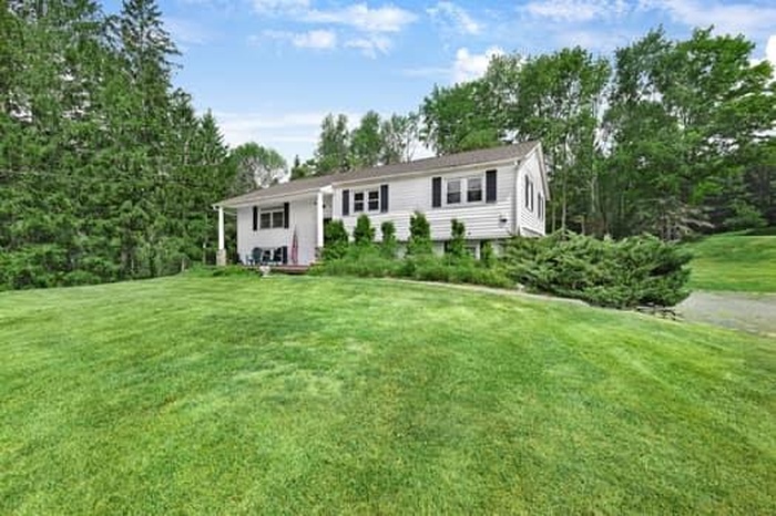 View of front of property featuring a front yard and view of scattered trees