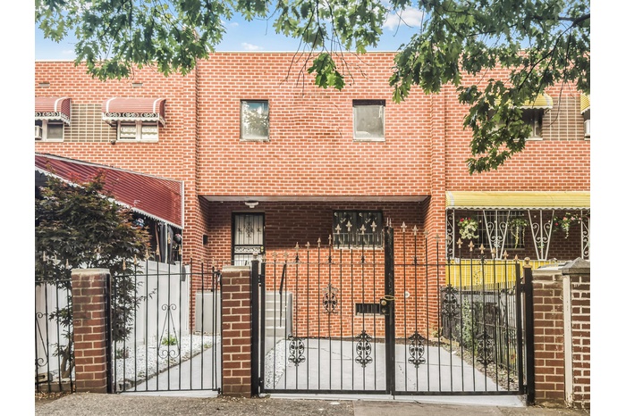 Traditional-style house with a fenced front yard, a gate, and brick siding