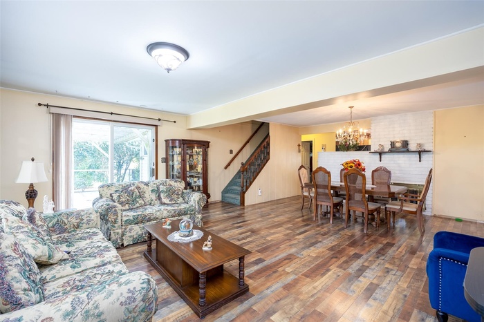 Living room featuring a chandelier, stairs, and wood finished floors