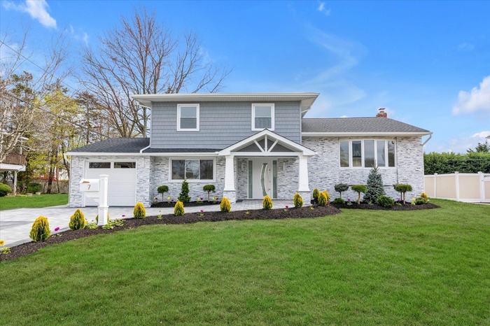 View of front of home featuring a garage, a chimney, driveway, and a shingled roof