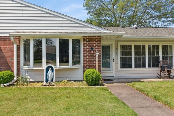 Doorway to property with brick siding and a yard