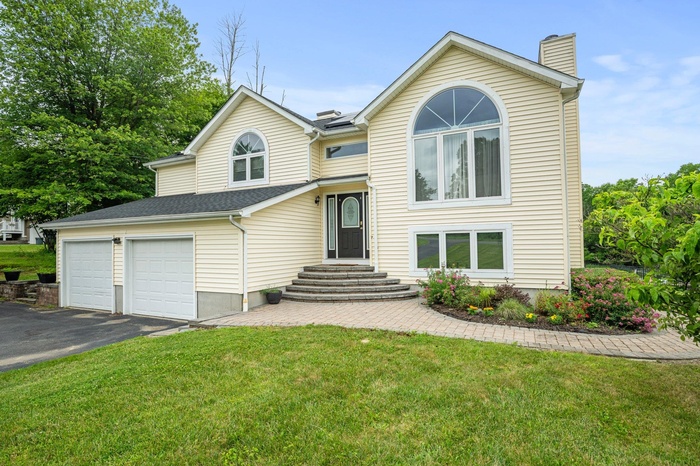Split foyer home with a chimney, asphalt driveway, and a front lawn