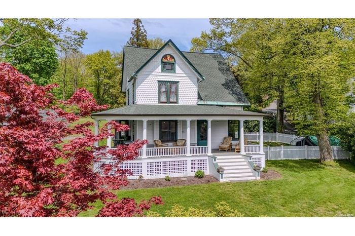 Victorian home with covered porch, a shingled roof, and stairs