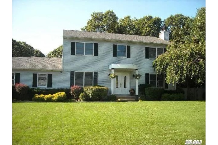 Colonial inspired home with a front yard and a chimney