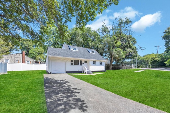 View of front facade with roof with shingles, asphalt driveway, and an attached garage