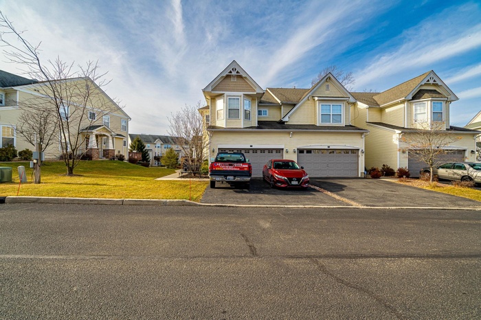 View of front of house with a garage, driveway, a residential view, and a front yard