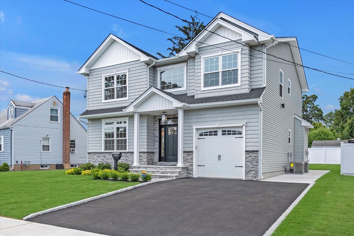Craftsman-style home with a garage, stone siding, roof with shingles, asphalt driveway, and board and batten siding